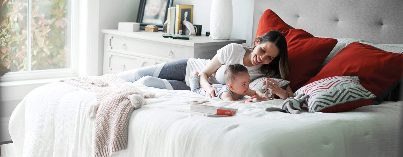 A mother and baby laying on a bed